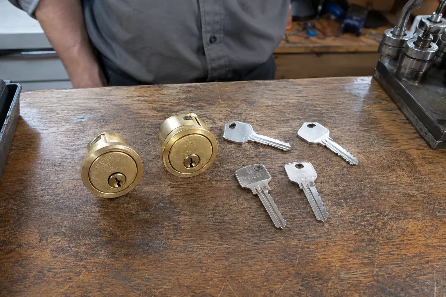 Two detached brass lock cylinders and four house keys on a wooden counter. — Lock Rekeying, Toronto